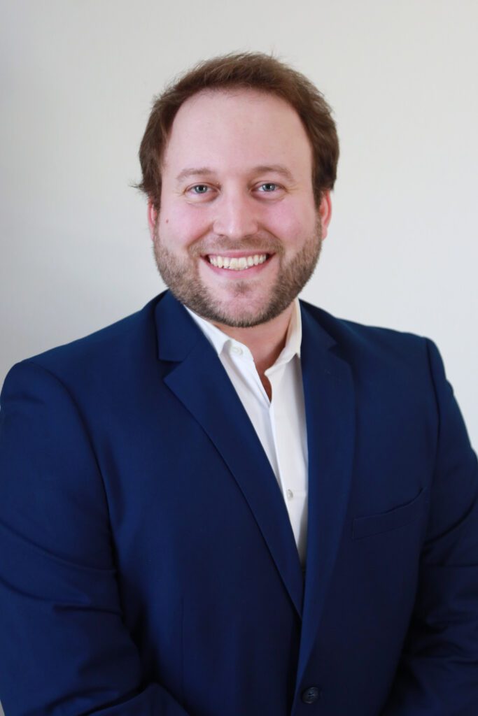 Smiling man in a blue suit jacket and white shirt.